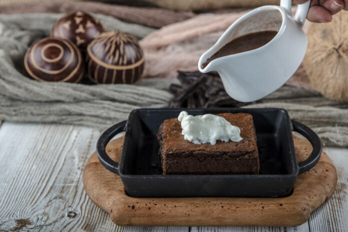 sizzling chocolate brownie is a sweet dish made using scoop of ice-cream on top served with a generous pouring of melted chocolate. server hot. selective focus.