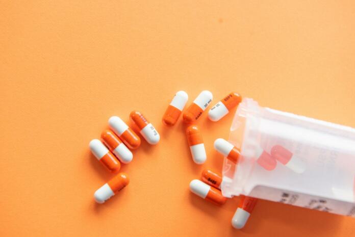 Prescription drugs on an orange background with a pill bottle. Orange pills.