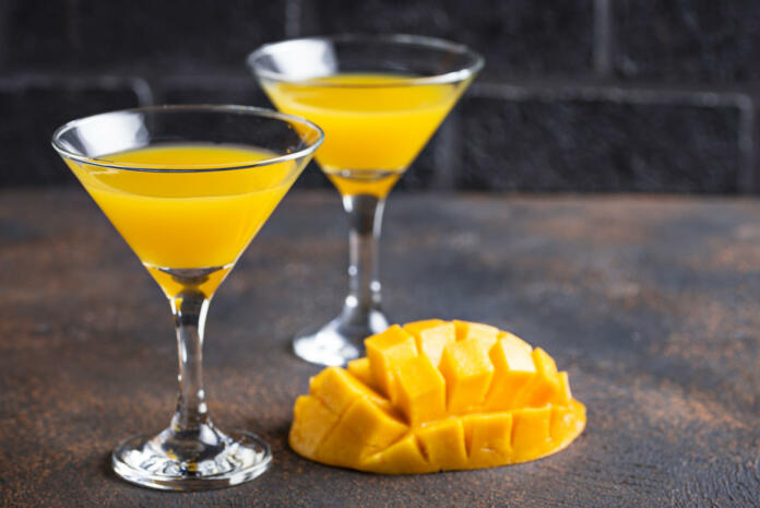 Tropical fruit cocktail with mango on dark background