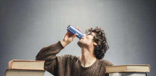 Young man drinking energy drink while studying. College student concept. Energizing before learning.