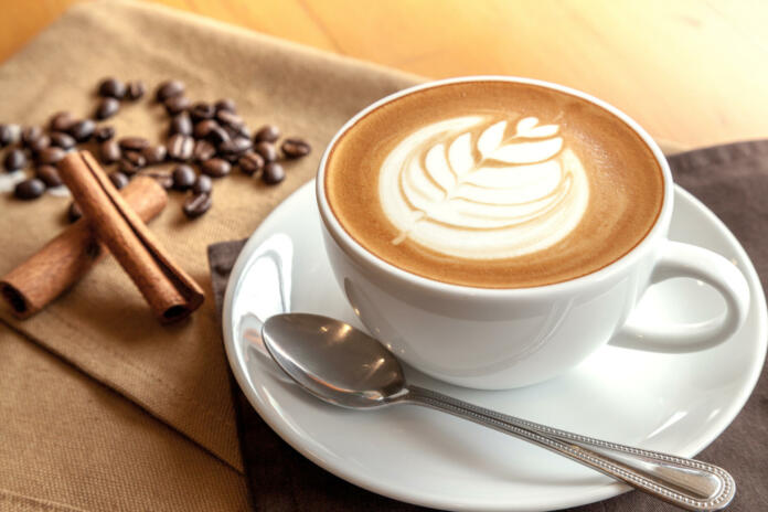 Cup of cafe' latte with coffee beans and cinnamon sticks