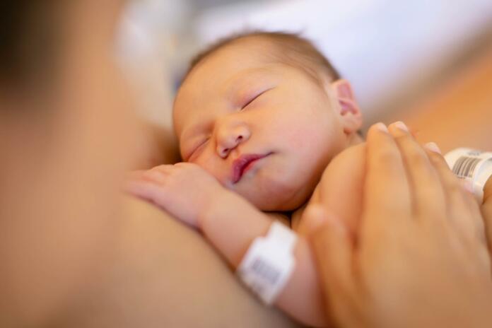 A mother holding her newborn baby on her warm chest for skin on skin time at the hospital.