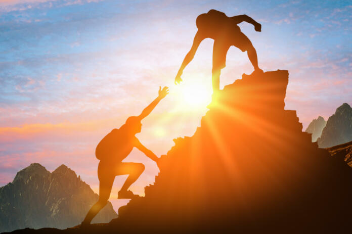 Help and assistance concept. Silhouettes of two people climbing on mountain thanks to mutual assistance and teamwork and partnership. business success and teamwork concept in company