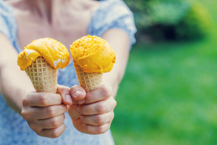 Woman's hands holding refreshing ice cream in waffle cones treats with a hint of zesty lemon flavour. With copy space