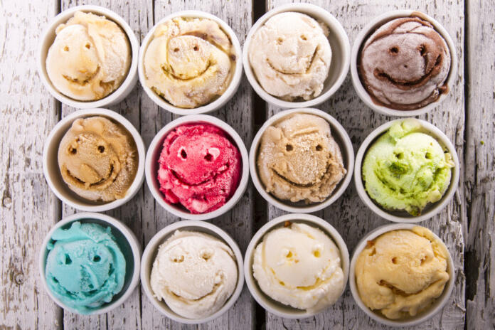 Selection of gourmet flavours of Italian ice cream in vibrant colors served on an old rustic wooden table in an ice cream parlor, overhead view