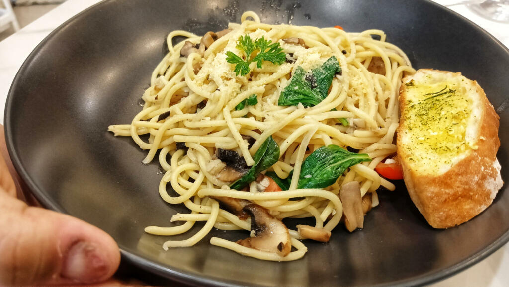 Spaghetti Aglio e Olio. Pasta with garlic, olive oil and chili served with slices of bread on a plate.