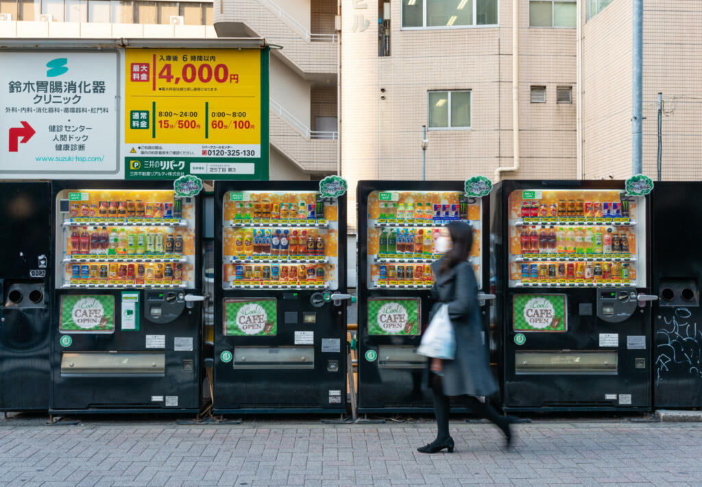 Tokyo, Japan - Mar 15, 2019: Woman wearing face mask walking past row of vending machines in Tokyo
