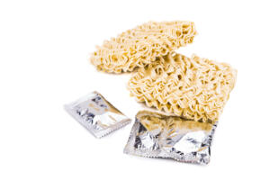 Uncooked instant noodles with flavoring packets on isolated white background