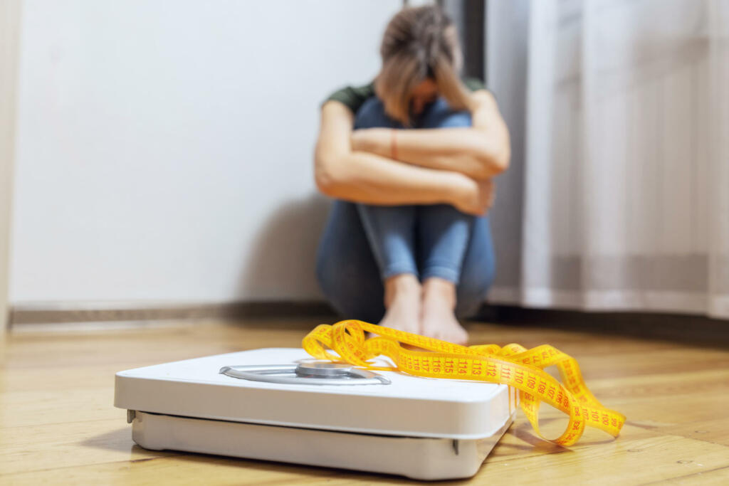 White scale and depression, upset and sad woman with measuring tape on wooden floor.
