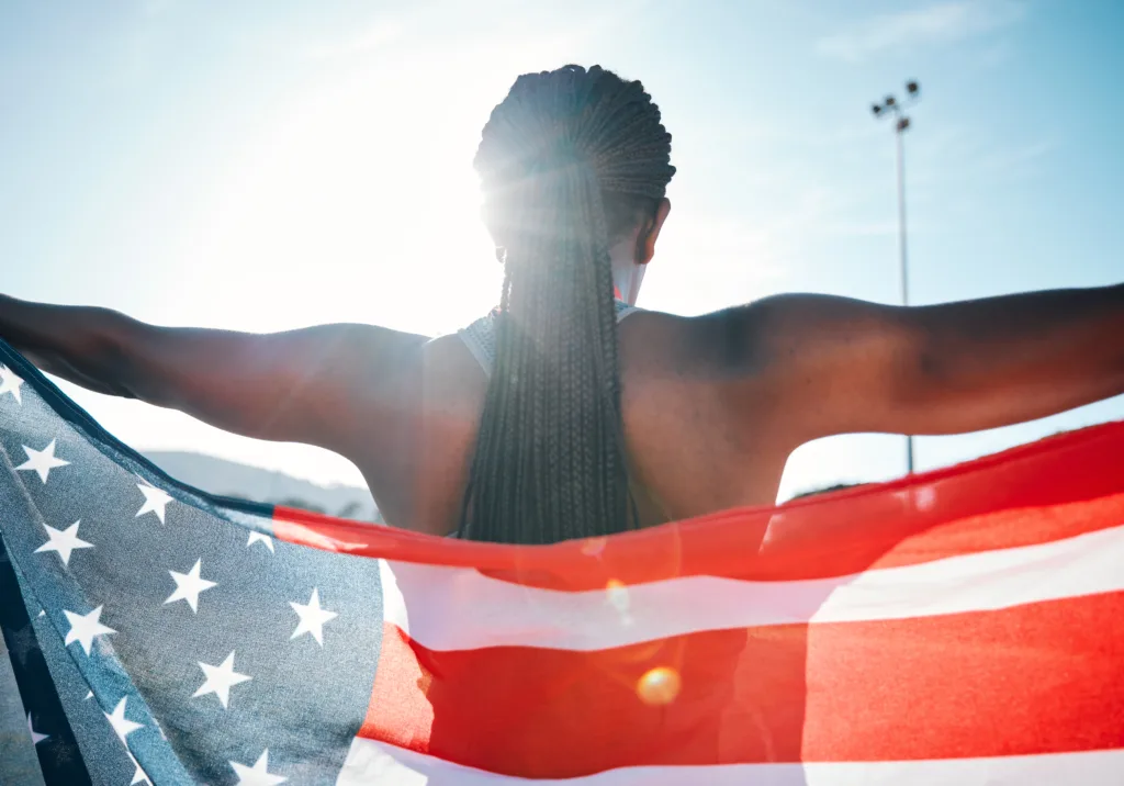 Athlete, American flag and sports with a woman outdoor at a stadium to celebrate country, pride and win. Back of a person for olympic sport, fitness and exercise achievement at competition in USA