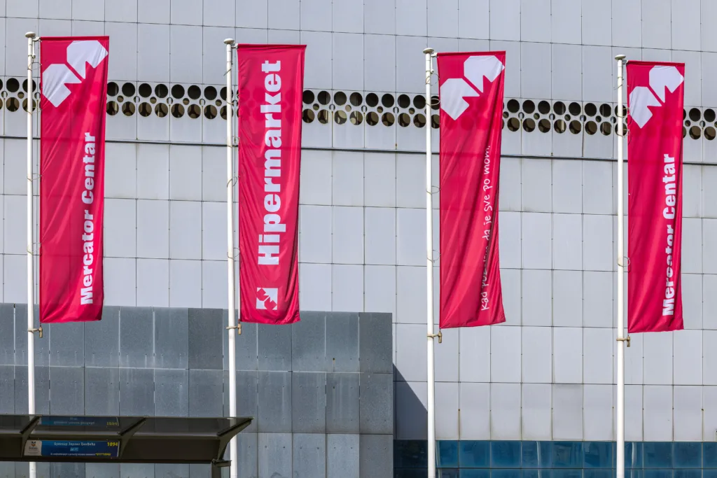 Belgrade, Serbia - March 13, 2023: Red Flags in Front of Mercator Hypermarket Store Shopping Centre Sunny Day.