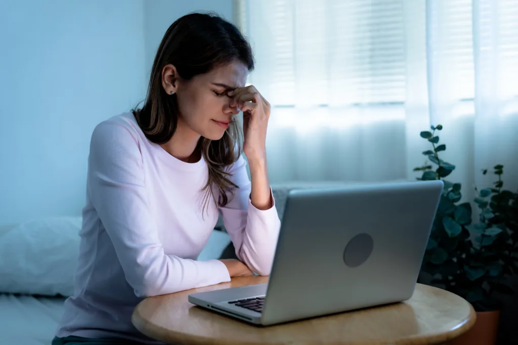 Caucasian woman tired from working overtime, She has eyestrain from looking at the computer screen for a long time, Blue light is harmful to the eyes.