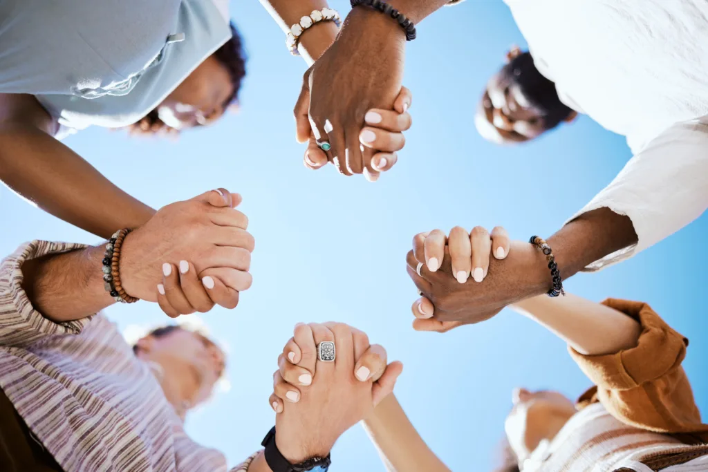 Diversity, people and hands in support, trust and unity for community against sky background. Diverse group hand holding together in united team building collaboration and teamwork solidarity success