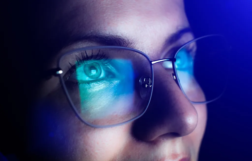 Girl works on internet. Reflection at the glasses from laptop.Close up of woman's eyes with black female glasses for working at a computer. Eye protection from blue light and rays.