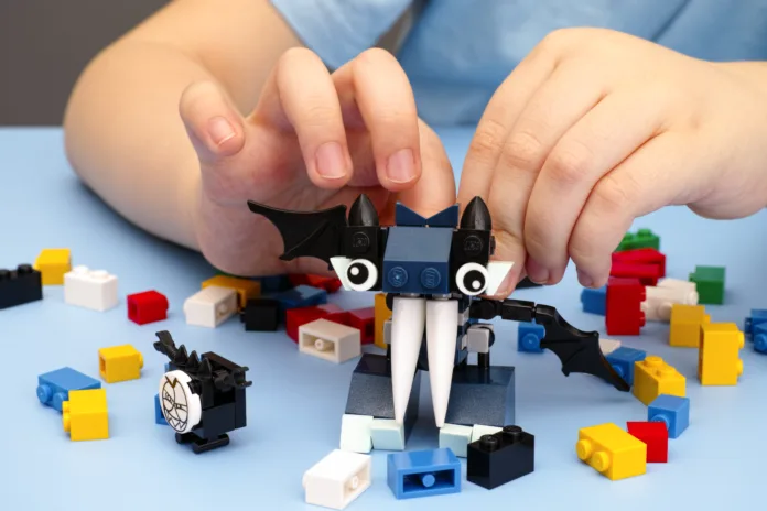 Tambov, Russian Federation - March 08, 2015: Child playing with Lego Mixel Vampos on blue table. There are some Lego bricks on table. Studio shot.