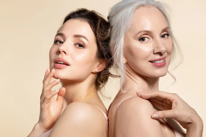 Two beautiful different age woman with perfect skin headshot portrait. Senior lady and young girl in underwear standing back-to-back posing for camera. Spa beauty salon procedure and home skincare