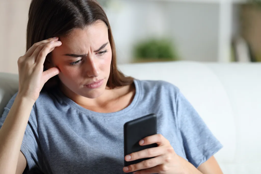 Worried girl checking smart phone at home