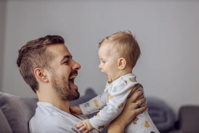 Caring father holding his only beloved adorable little boy and teaching him to talk.