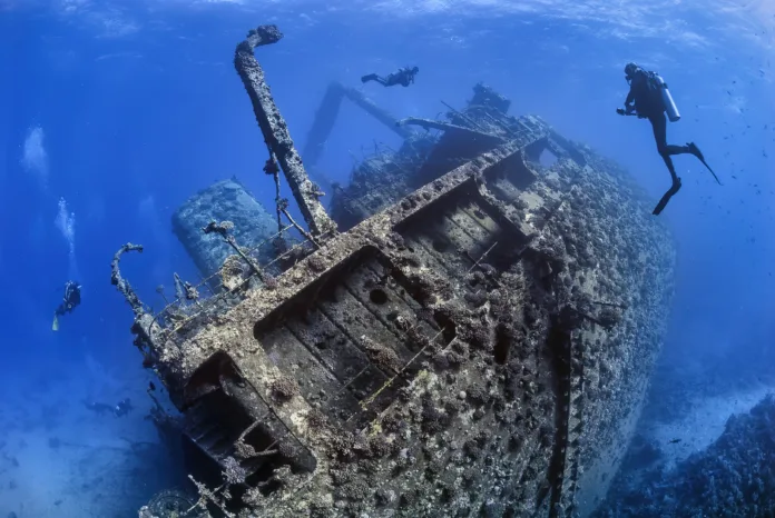 Divers exploring the outside of a shipwreck