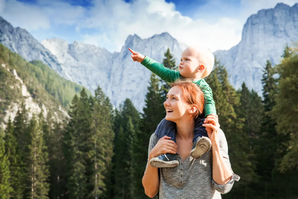 Happy mother and her child looking forward and pointing to sky. Family on trekking day in the mountains. Mangart, Julian Alps, National Park, Slovenia, Europe. Travel, Explore, Family, Future Concept