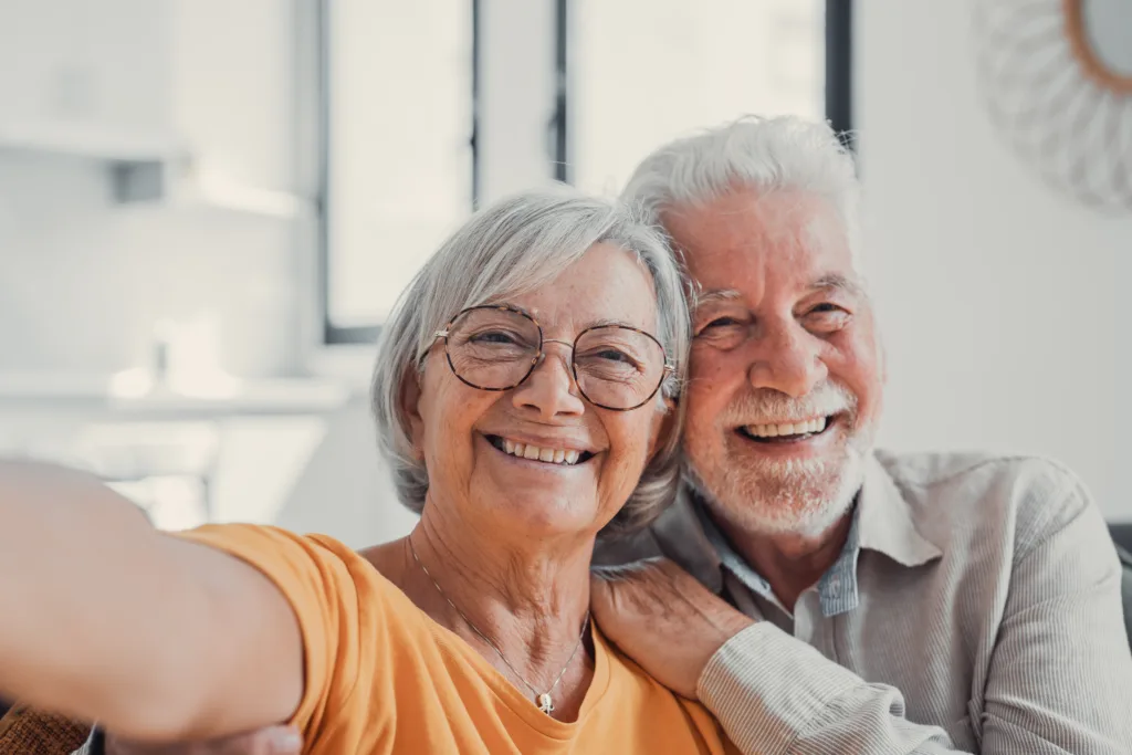 Head shot portrait happy senior couple taking selfie, having fun with phone cam, smiling aged wife and husband hugging, looking at camera, posing for photo, aged man vlogger recording video