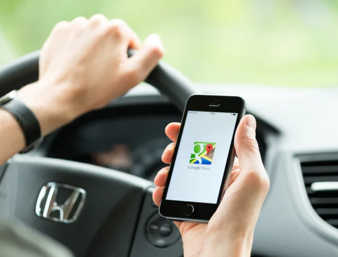 Kiev, Ukraine - May 16, 2014: Man in the car planning a route using a Google Maps application on Apple iPhone 5S. Google Maps is a most popular web mapping service for mobile  provided by Google inc.