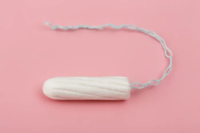 Medical female tampon on a pink background. Hygienic white tampon for women. Cotton swab. Menstruation, means of protection. Tampons on a red background.