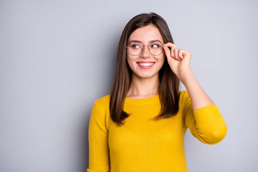 Portrait of attractive cheerful clever girl touching specs looking aside copy space isolated over grey color background.