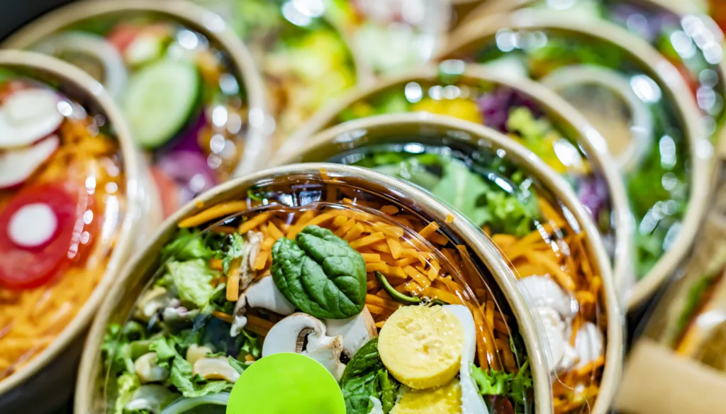 Pre-packaged vegetable salads displayed in a commercial refrigerator