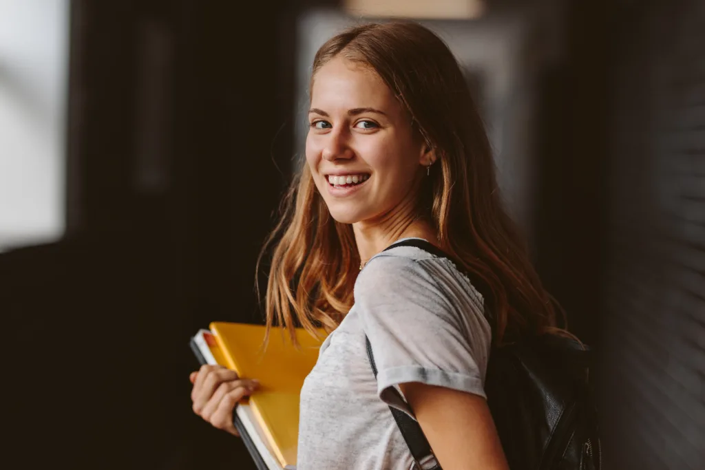 Rear view of beautiful girl walking through university hallway looking back and smiling. female student going for the lecture.