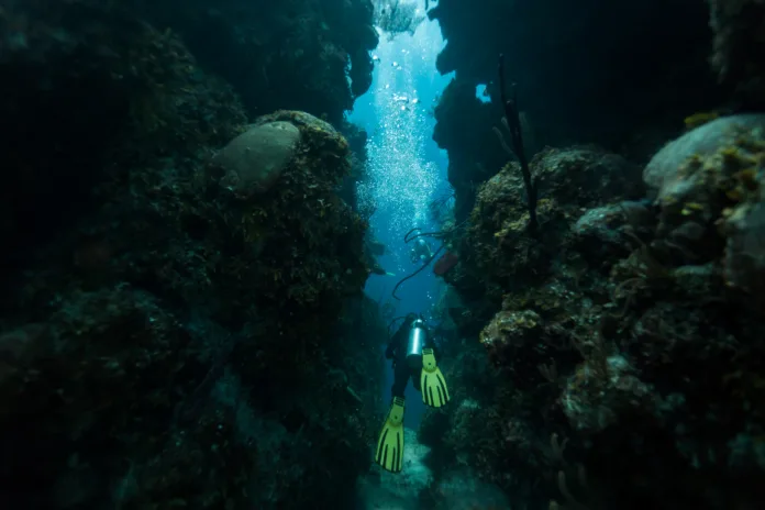 Scuba diver swims through tunnel in Blue Hole Caribbean Sea Belize