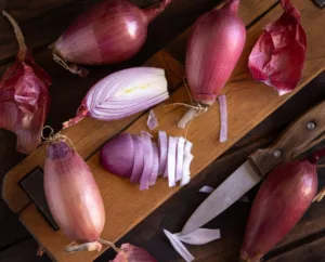 Sliced Red tropea onions with a knife on a wooden board top view. Traditional local south italian vegetable. Cooking process in home kitchen