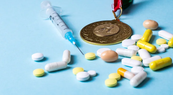 Syringe, medals and pills on a blue background. Doping in sports. Abuse of anabolic steroids for sports. Sports fraud. Doping athletes.