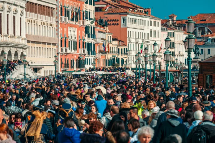 VENICE, ITALY - FEBRUARY 18, 2017: Crowds of tourists walking by typical venetian buildings near San Marco Square during famous  traditional carnival taking place each year in Venice, Italy.