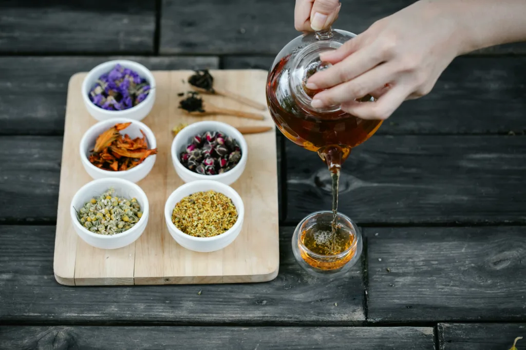 Woman pouring herbal tea into a glass teacup