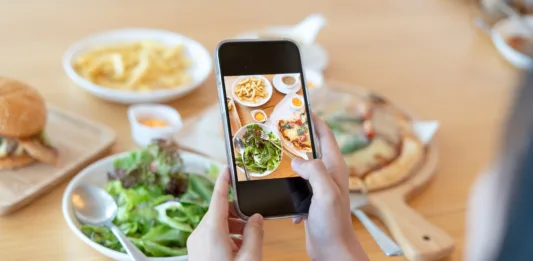 Woman take picture of a meal on the table after ordering food online to eat at home. Photography and use phone concepts