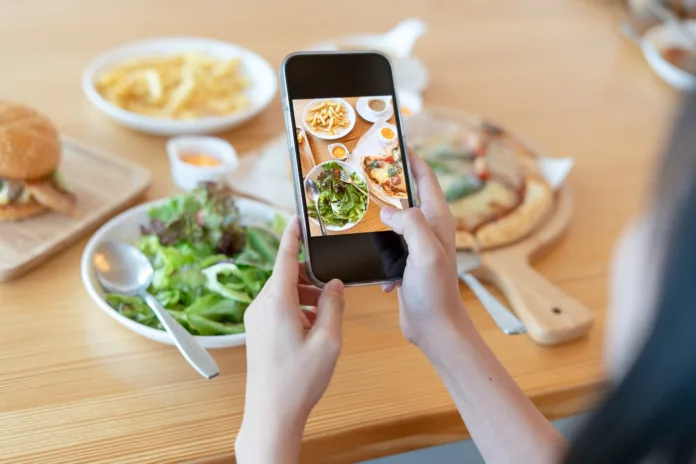 Woman take picture of a meal on the table after ordering food online to eat at home. Photography and use phone concepts