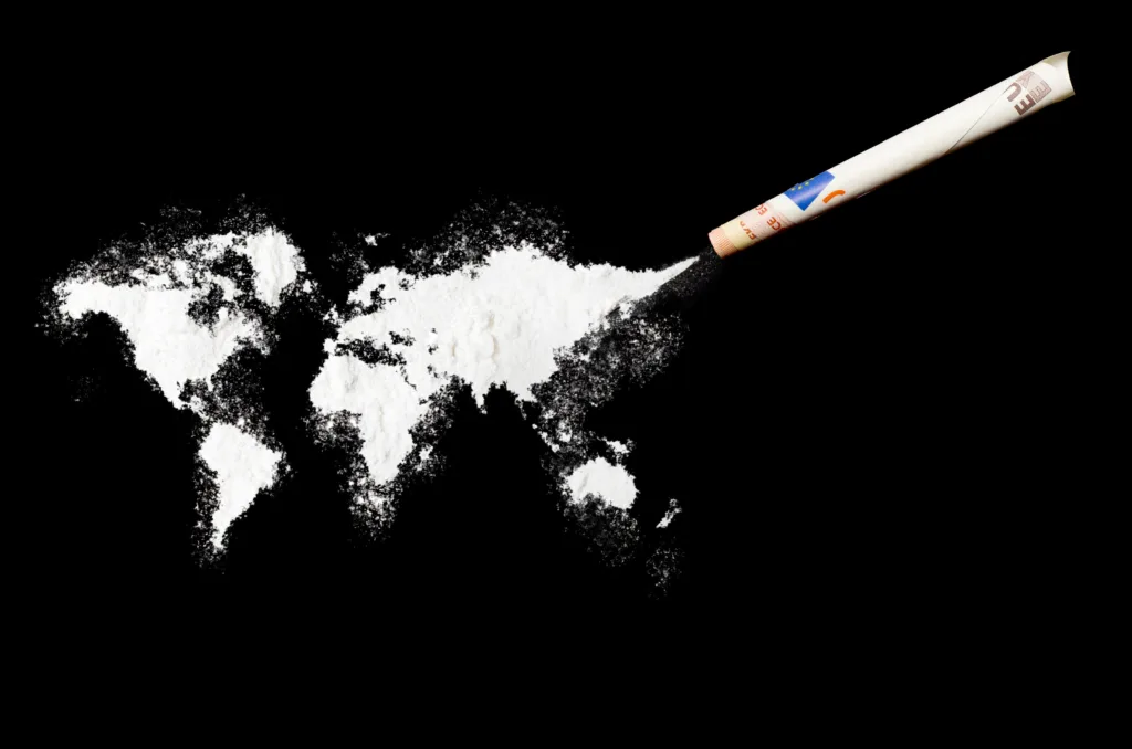 A top shot of a powder drug like cocaine in the shape of the world (Continent) with a rolled money bill.(series).Inspired by the world we do live in.