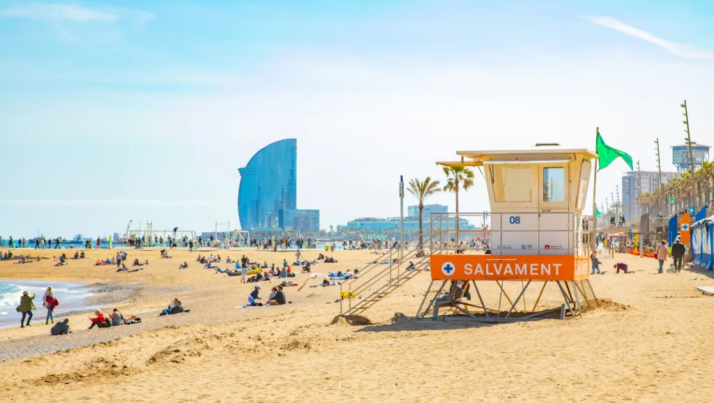 Barcelona, Spain - 12 April, 2023: Platja de la Barceloneta (Barceloneta beach) in Barcelona city, people chilling on the beach.