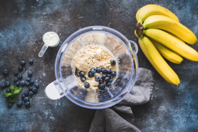 Blueberry protein powder in blender, smoothie preparation, top view. Concept of fitness healthy eating, clean eating, sport lifestyle