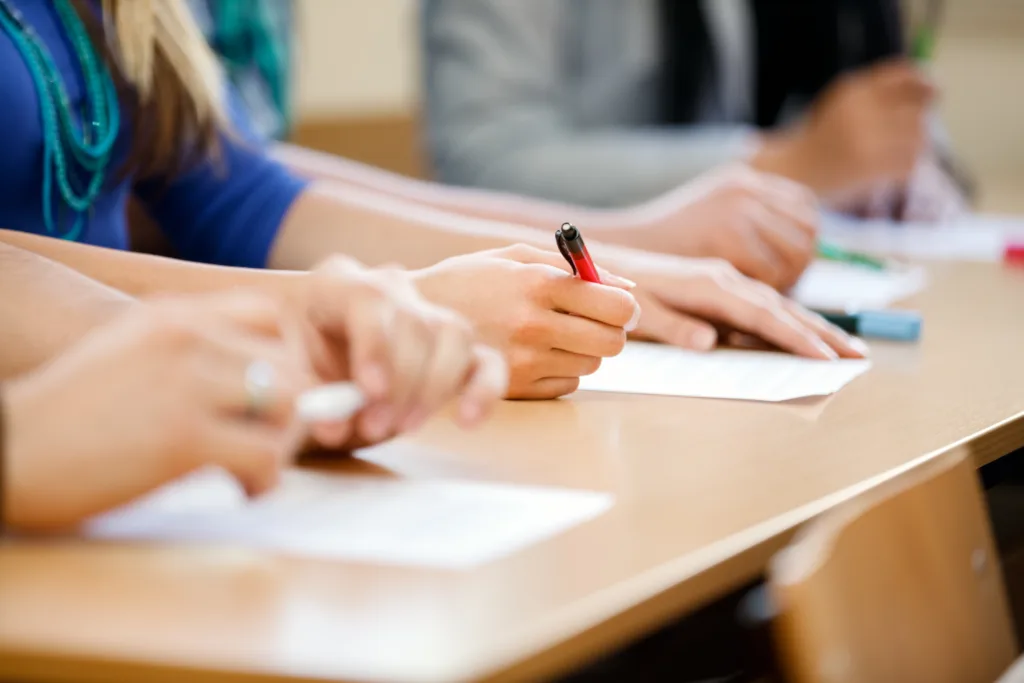 Close-up of writing hands of students at course