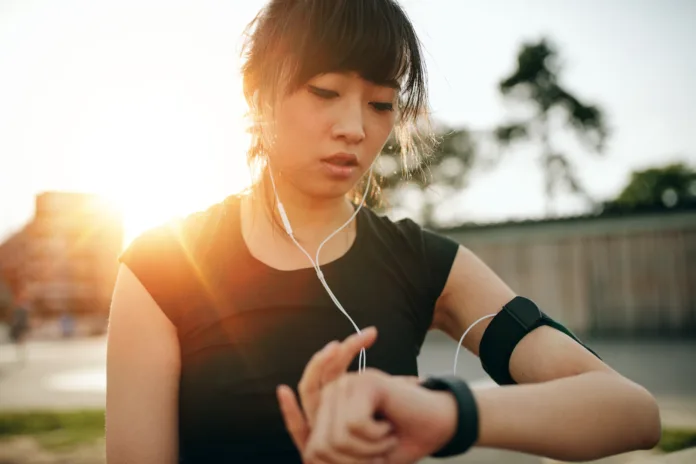 Close up shot of young sportswoman looking at smartwatch. Fitness female monitoring her progress on smartwatch.