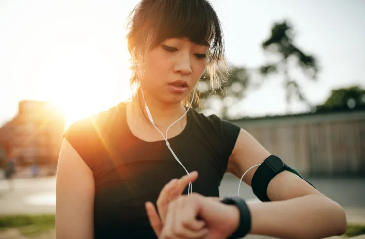 Close up shot of young sportswoman looking at smartwatch. Fitness female monitoring her progress on smartwatch.