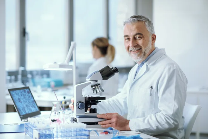 Confident smiling researcher sitting at desk and working in the medical lab