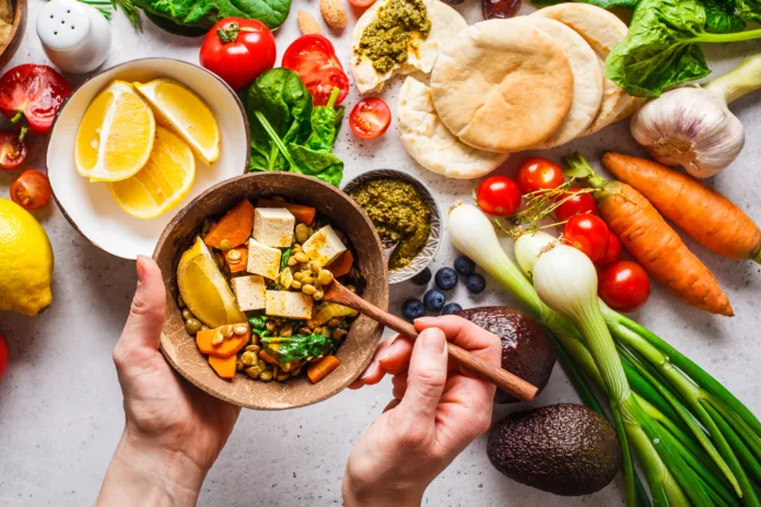 Healthy vegetarian food background. Vegetables, hummus, pesto and lentil curry with tofu.