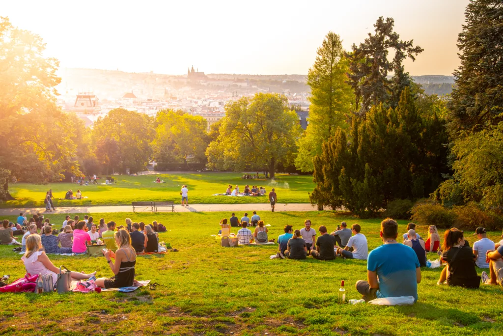 PRAGUE, CZECH REPUBLIC - AUGUST 17, 2018: Sunset in Rieger Gardens, Riegrovy sady, in Prague. Many people sitting in the grass and enjoying sunny summer evening and lookout of Prague historical city centre. Czech Republic.