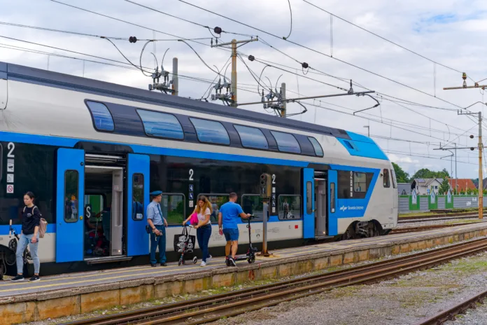 Scenic view of blue and white train at railway station of City of Skofja Loka on a cloudy summer day. Photo taken August 9th, 2023, Škofja Loka, Slovenia.