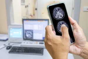 The doctor is using a cell phone to check the patient's brain MRI results. The background is an electromagnetic control room. medical technology concept