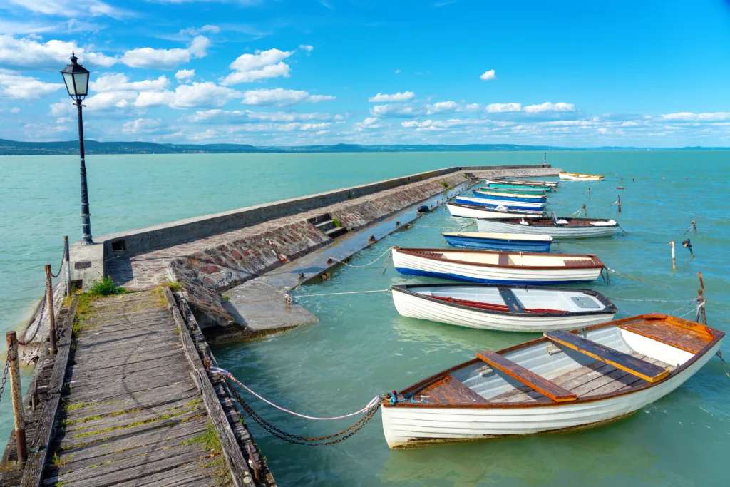 wooden pier in Balatonlelle with colorful boats on lake Balaton blue sky and .