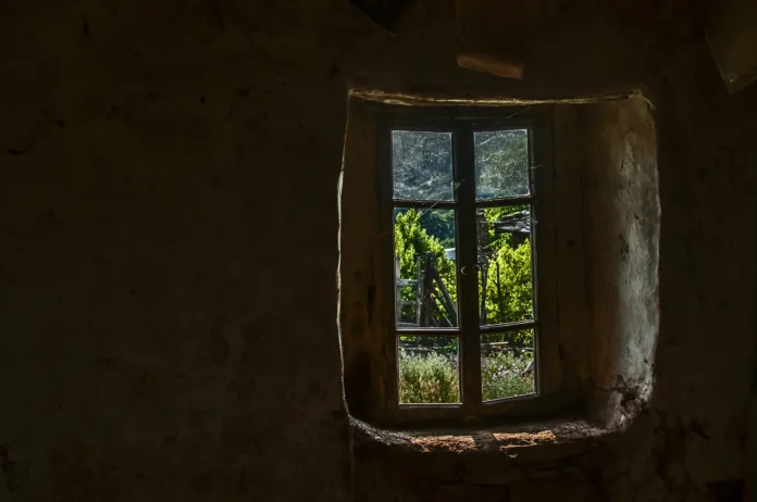 Wooden window of old abandoned neglected country house with view from inside